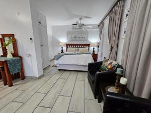 a bedroom with a bed and a couch and a chair at Ndiza Lodge and Cabanas in St Lucia