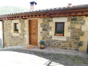 uma casa de pedra com uma porta de madeira e duas janelas em Casa del Horno em Potes