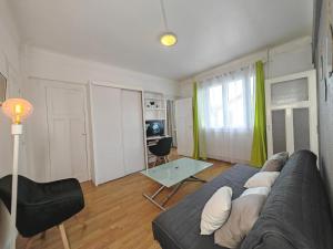 ein Wohnzimmer mit einem Sofa und einem Tisch in der Unterkunft Balcon / 2 pièces aux Lilas in Les Lilas