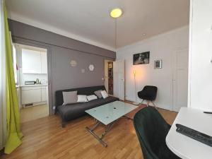 ein Wohnzimmer mit einem Sofa und einem Tisch in der Unterkunft Balcon / 2 pièces aux Lilas in Les Lilas