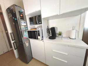 eine Küche mit weißen Schränken und einem Kühlschrank in der Unterkunft Balcon / 2 pièces aux Lilas in Les Lilas
