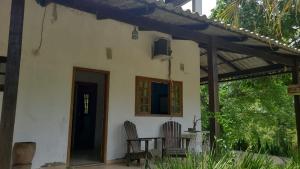 une terrasse couverte d'une maison avec deux chaises et une table dans l'établissement Pousada Riacho da Serra, à Penedo