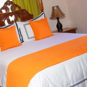 a bed with orange and white sheets and a lamp at Windbreak Villa in Buff Bay