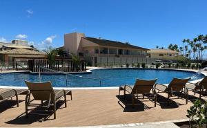 a group of chairs sitting next to a swimming pool at Village pé na areia com limpeza in Lauro de Freitas