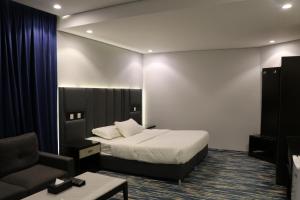 Habitación de hotel con cama y silla en قمم بارك Qimam Park Hotel 1 en Abha