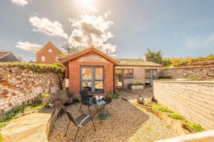 a home with a stone wall and a patio at Duffields Cottage in Brancaster