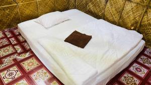 un letto bianco con un cuscino marrone di NLCO Homestay a Siem Reap