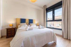 a bedroom with a large white bed with a large window at MalagaSuite Comfortable Home Apartments in Málaga