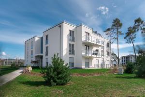 un edificio bianco con un albero di fronte di Ferienwohnung "Haffsonne" - Whg 7 10 a Zirchow