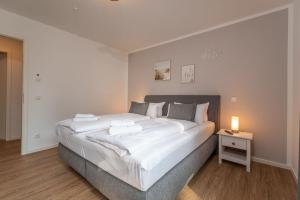 a large white bed in a room with a night stand at Ferienwohnung "Haffsonne" - Whg 7 10 in Zirchow