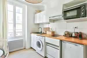 een witte keuken met een wasmachine en droger bij Pretty 24 m near Batignolles in Parijs