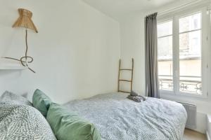 een woonkamer met een bank en een raam bij Pretty 24 m near Batignolles in Parijs