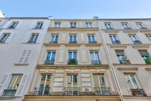 een hoog wit gebouw met ramen en balkons bij Pretty 24 m near Batignolles in Parijs