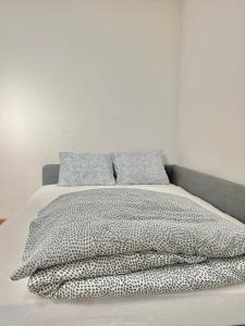 uma cama com um edredão e almofadas preto e branco em Appartamento per 4 persone em Rudolfstetten