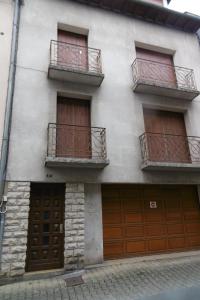 a white building with brown doors and balconies at Gîte l' Odyssée in Espalion