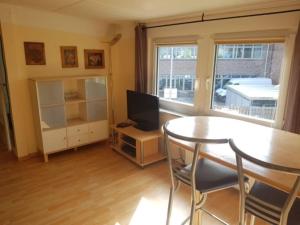 een woonkamer met een tafel en een televisie bij Haus Mara in Emden