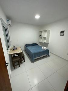 um quarto com uma cama azul e uma mesa em RESIDENCIAL WRUBLESKI ANEXO em Palhoça