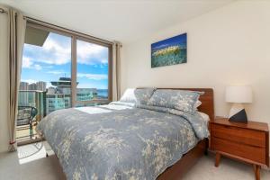 - une chambre avec un lit et une grande fenêtre dans l'établissement Sky Ala Moana 2907 condo, à Honolulu