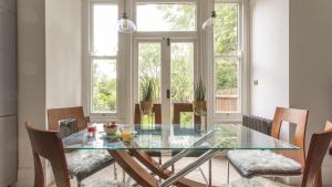 uma sala de jantar com uma mesa de vidro e cadeiras em Stunning 4-Bed Property in London-Parking & Garden em Londres