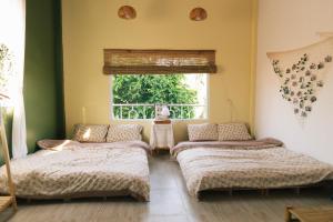dwa łóżka w pokoju z oknem w obiekcie Entire House - Nhà nguyên căn - Nhà Mơ Homestay Bến Tre w mieście Ben Tre