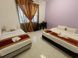 a bedroom with two beds and a window with a table at Taman Bahagia Homestay in Temerloh