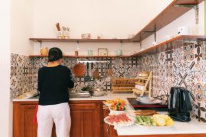 a woman standing in a kitchen preparing food at Entire House - Nhà nguyên căn - Nhà Mơ Homestay Bến Tre in Ben Tre