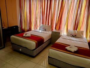 two beds in a room with colorful curtains at Taman Bahagia Homestay in Temerloh
