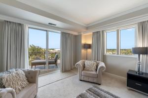 a living room with a couch and a chair and windows at Ocean View Residence 608 located at The Ritz-Carlton in Upper Land