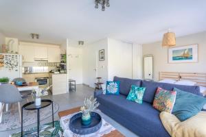 a living room with a blue couch and a kitchen at La Baraka - Beau studio dans parc arboré in Marseille +6 photos