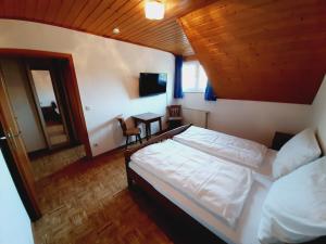 a bedroom with a bed and a tv in it at Pension Dorfengel in Berolzheim
