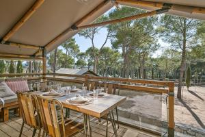 a wooden table and chairs on a deck with trees at Càmping Castell Montgrí **** in L'Estartit