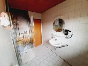 a bathroom with a shower and a sink and a mirror at Pension Dorfengel in Berolzheim
