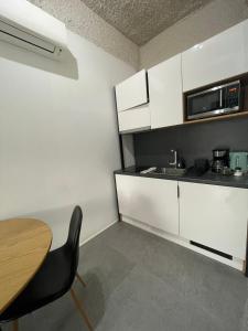 cocina con armarios blancos, mesa y fregadero en Jazz Apartment, en Budapest