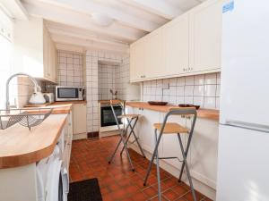 a kitchen with white cabinets and a red tile floor at Wharf Cottage in Llangollen +43 photos