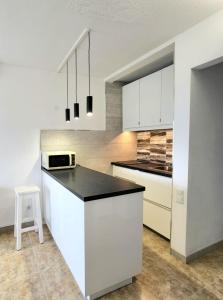 プラヤ・デル・イングレスにあるValparaiso Top Floorのキッチン(白いキャビネット、黒いカウンタートップ付)