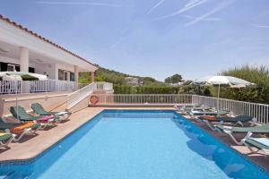 a swimming pool with chairs and an umbrella at Villa Santo Grande by Villa Plus in Santo Tomás