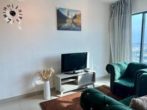 Una sala de estar con un televisor de pantalla plana y un sofá. en Welcome Suite at Trefoil Setia Alam, en Shah Alam