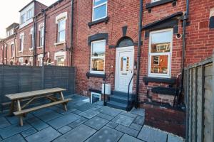 un banco de madera sentado frente a un edificio de ladrillo en Homebird Property - Haddon House en Leeds