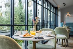 a table with a plate of food on it in a room with windows at Maison ELLE Amsterdam in Amsterdam