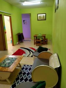 een woonkamer met groene muren en een tafel bij JAMSYIR HOMESTAY BAJET in Pendang