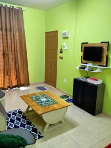 een woonkamer met een tafel en een televisie bij JAMSYIR HOMESTAY BAJET in Pendang