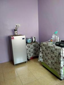 een keuken met een witte koelkast en 2 tafels bij JAMSYIR HOMESTAY BAJET in Pendang