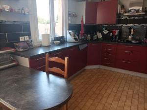 a kitchen with red cabinets and a table with a chair at Maison proche circuit 24 heures du mans in Spay