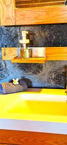 ein gelbes Waschbecken mit einem Regal an der Wand in der Unterkunft Maison Harmonie Atypique in Saint-Leu