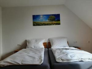 - 2 lits dans une chambre avec un arbre sur le mur dans l'établissement Ferienwohnung Dorfengel, à Berolzheim