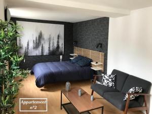 ein Schlafzimmer mit einem Bett und einem Sofa in der Unterkunft Les Appartements de St-Etienne in Fécamp