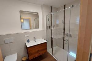 een badkamer met een wastafel en een douche met een glazen deur bij Siedls Enzian in Hirschegg Rein