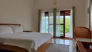 a bedroom with a bed and a large window at The Ixora - A Boutique Homestay in Varkala