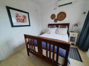 a bedroom with a wooden bed in a room at Cottage On the Beach in Umdloti