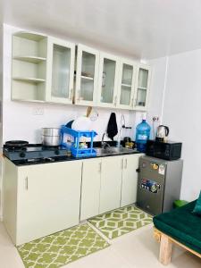 La cuisine est équipée de placards blancs et d'un réfrigérateur gris. dans l'établissement Emerald BnB, à Ruaka